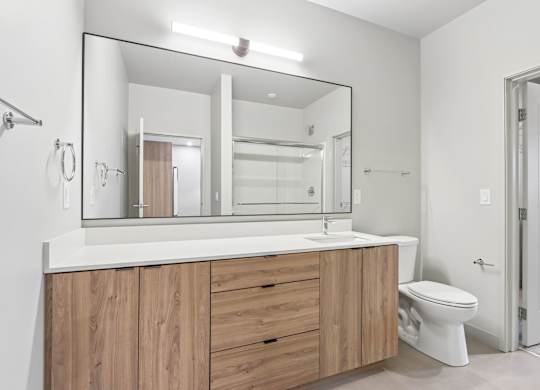 A bathroom with a white countertop and wooden cabinets.
