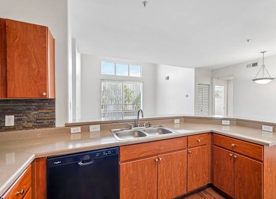 A kitchen with wooden cabinets and a black dishwasher.