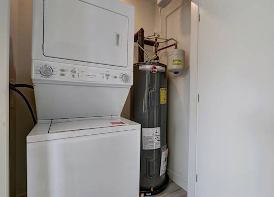 A white dishwasher and a water heater are installed in a small room.
