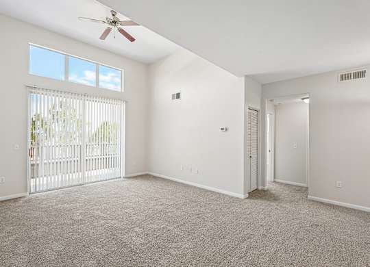 A room with a ceiling fan and carpeted floor.