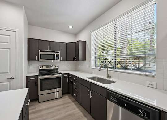 A modern kitchen with stainless steel appliances and dark brown cabinets.