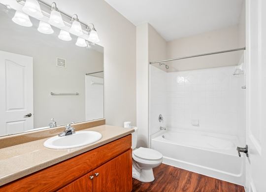 A white bathroom with a wooden vanity and a white bathtub.