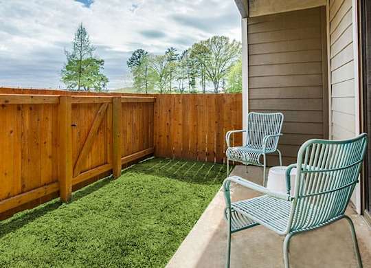 a patio with two chairs and a fence