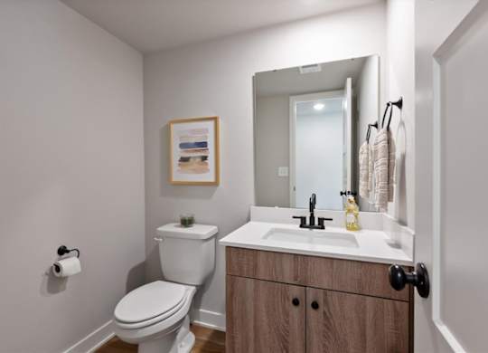A bathroom with a toilet, sink, and a mirror.