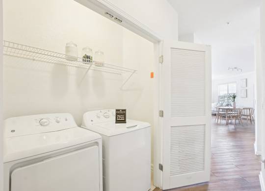 A white washing machine and dryer are in a small laundry room.