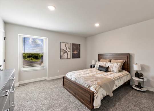 A bedroom with a large bed and a window with blinds.