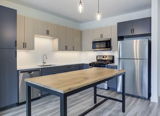 A modern kitchen with a wooden table and stainless steel appliances.