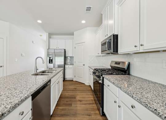 A kitchen with granite countertops and white cabinets.