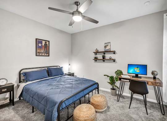 a bedroom with a bed and a desk with a computer