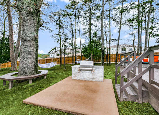 a patio with a grill and a tree