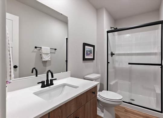 A white bathroom with a black sink and a white toilet.