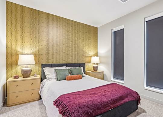 A bedroom with a bed, nightstands, and lamps.