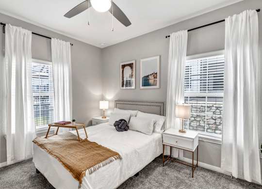 a bedroom with a bed and two windows