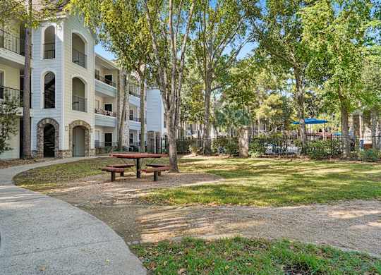 A park with a picnic table and apartment buildings in the background.