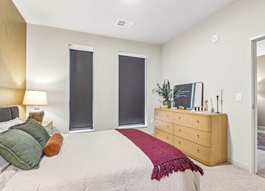 A bedroom with a bed, nightstand, and a dresser with a mirror.