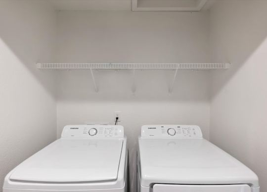 Two white washing machines in a small laundry room.