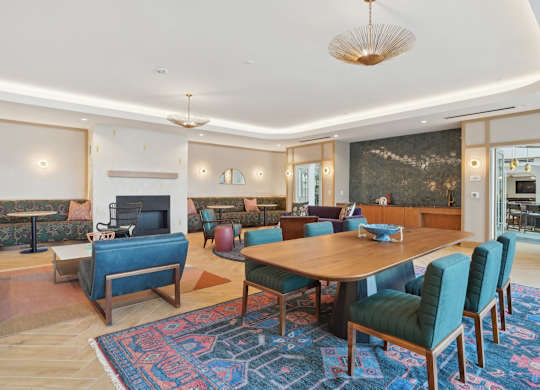 A living room with a blue rug and a wooden table.