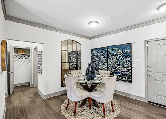 A dining room with a table set for two and a large painting on the wall.