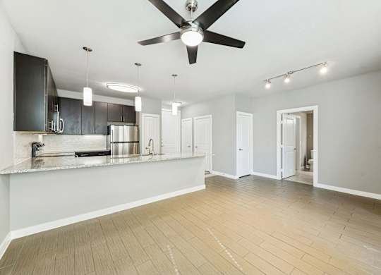 A spacious kitchen with a ceiling fan and lighting fixtures.