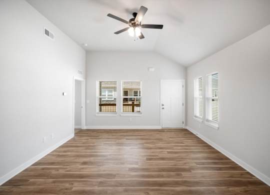 A room with a ceiling fan and wooden flooring.