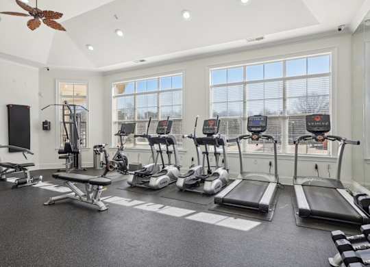 A spacious gym with treadmills, elliptical machines, and a fan.