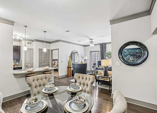 A modern dining room with a glass table and white chairs.