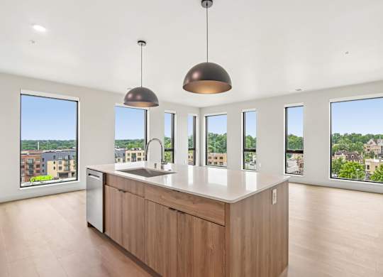 A kitchen with a large island and pendant lights.
