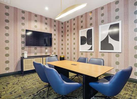 A conference room with a long table and blue chairs.