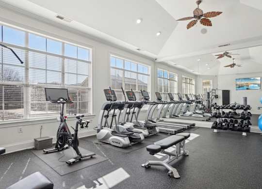 A spacious gym with a variety of exercise equipment and a ceiling fan.