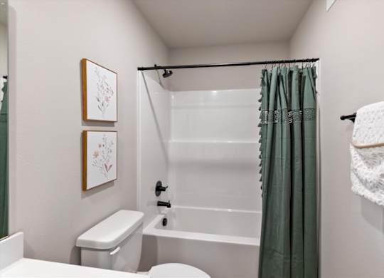 A white toilet sits next to a white bathtub in a small bathroom.