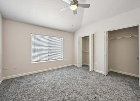 A room with a ceiling fan and carpeted floor.