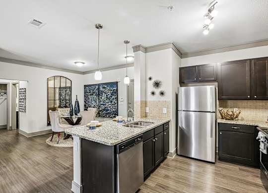 A kitchen with a stainless steel refrigerator and black cabinets.