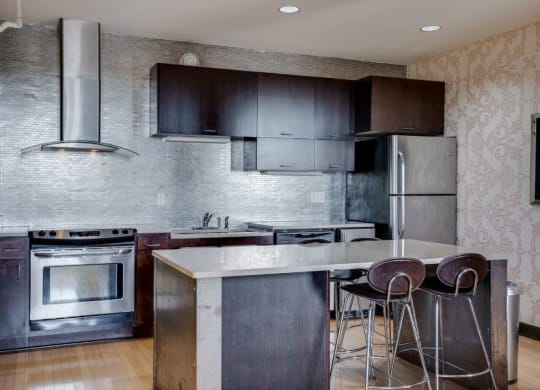 a kitchen with stainless steel appliances and a bar with three stools C&E Living in St Paul, MN