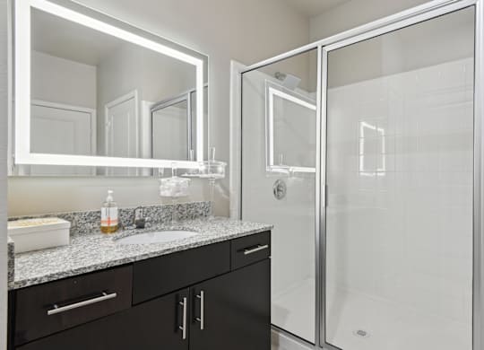 A bathroom with a sink, mirror, and shower.