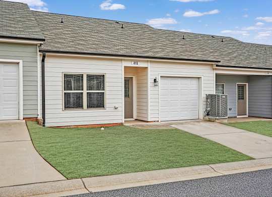 A row of houses with garages and a green lawn in front.