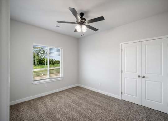A room with a ceiling fan and a window with blinds.