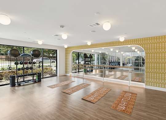 A gym with a yellow wall and wooden floor.