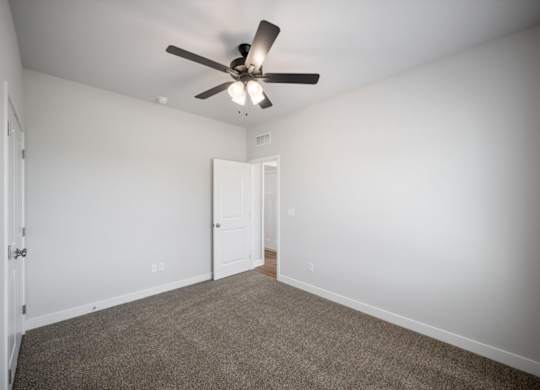 A room with a ceiling fan and carpeted floor.