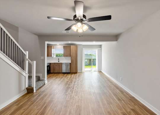 A spacious room with a ceiling fan and wooden flooring.