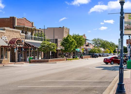 A street view of a small town with a red car parked on the side of the road.