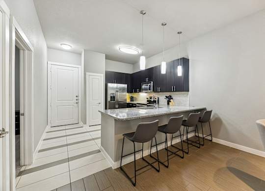A kitchen with a bar and chairs.