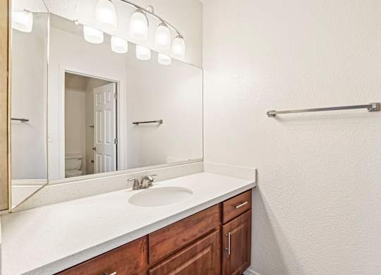 A bathroom with a sink, mirror, and lights.