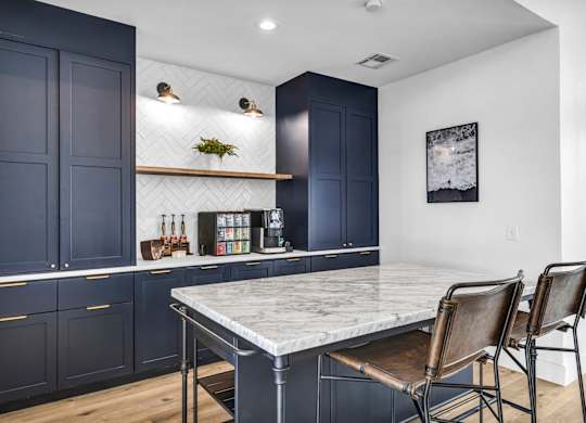resident lounge with a kitchen with navy cabinets and a marble countertops