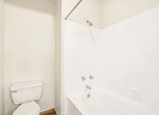 A white toilet and bathtub in a bathroom.