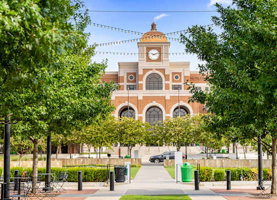 A clock tower is at the center of a building with arched windows.