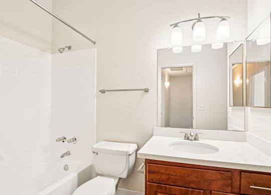 A white bathroom with a toilet, sink, and mirror.