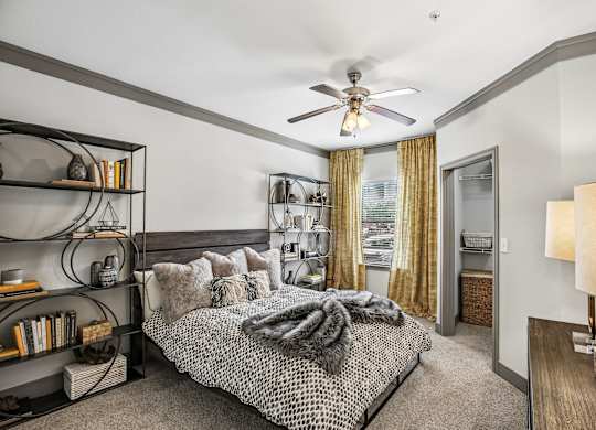 A bedroom with a bed, a ceiling fan, and a bookshelf.