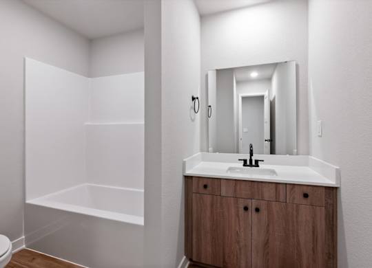 A bathroom with a white sink and a wooden cabinet.