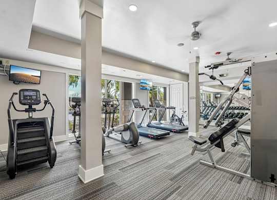 A spacious gym with a variety of equipment including treadmills, elliptical machines, and weight machines.