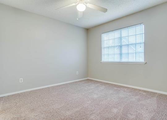 an empty room with a window and a ceiling fan